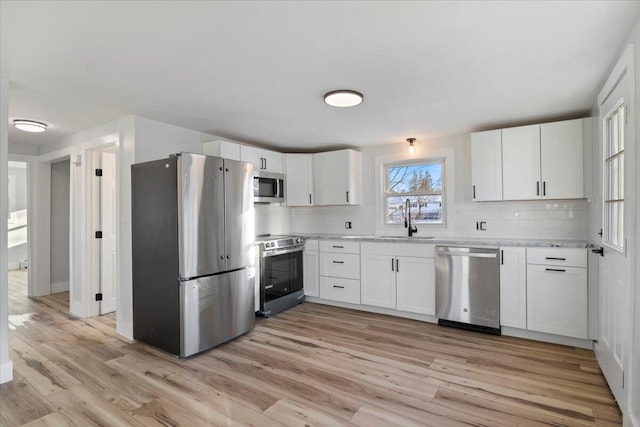 kitchen featuring stainless steel appliances, white cabinets, and light wood-type flooring