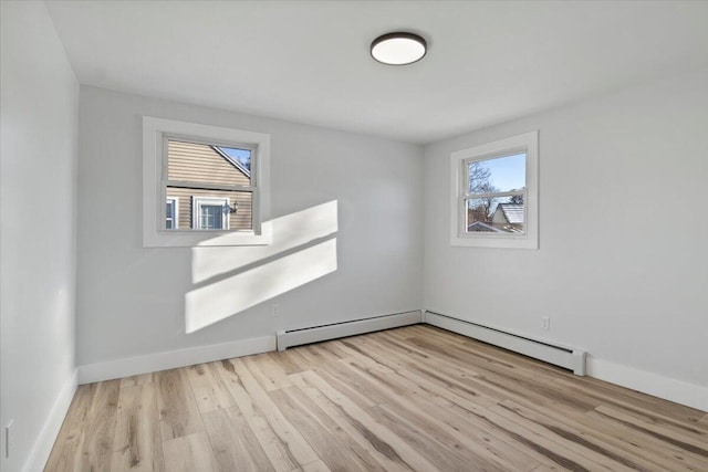 unfurnished room featuring baseboard heating and light wood-type flooring