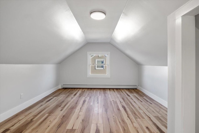 additional living space featuring baseboard heating, light wood-type flooring, and lofted ceiling