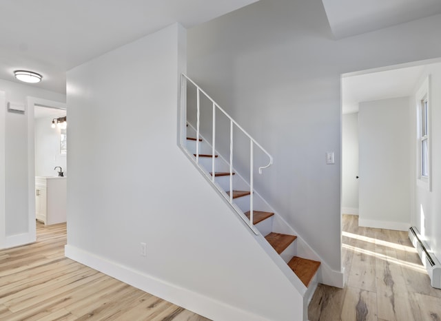 stairs with sink, hardwood / wood-style flooring, and baseboard heating