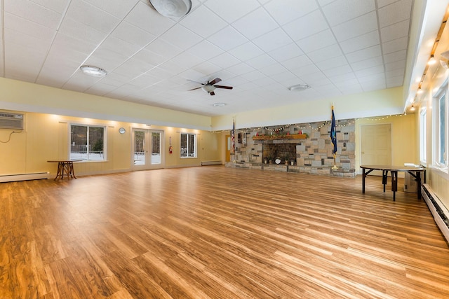 unfurnished living room featuring ceiling fan, light hardwood / wood-style floors, a wall mounted air conditioner, and a baseboard radiator