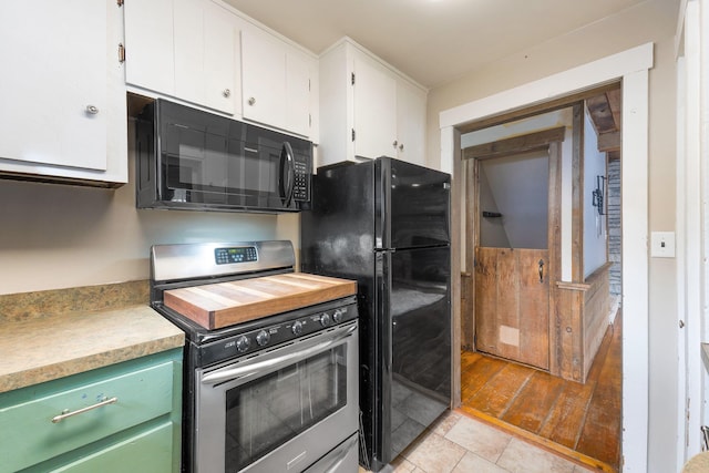 kitchen featuring white cabinets, green cabinetry, light tile patterned flooring, and black appliances