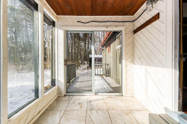 unfurnished sunroom featuring a healthy amount of sunlight and wooden ceiling