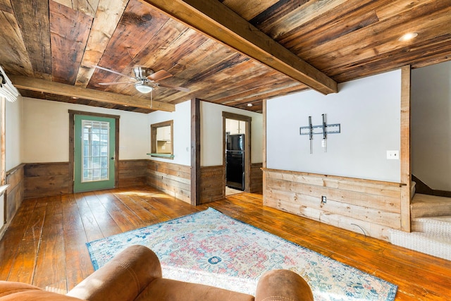 interior space with wood ceiling, wood-type flooring, beamed ceiling, ceiling fan, and wooden walls