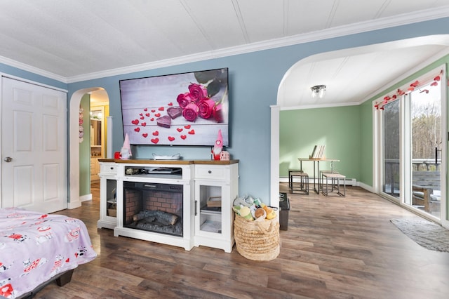 bedroom with dark wood-type flooring, crown molding, and a fireplace