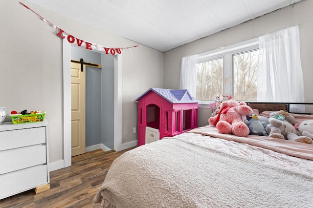 bedroom with a barn door and dark hardwood / wood-style flooring