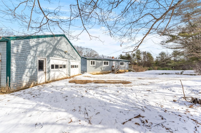 snow covered rear of property featuring a garage