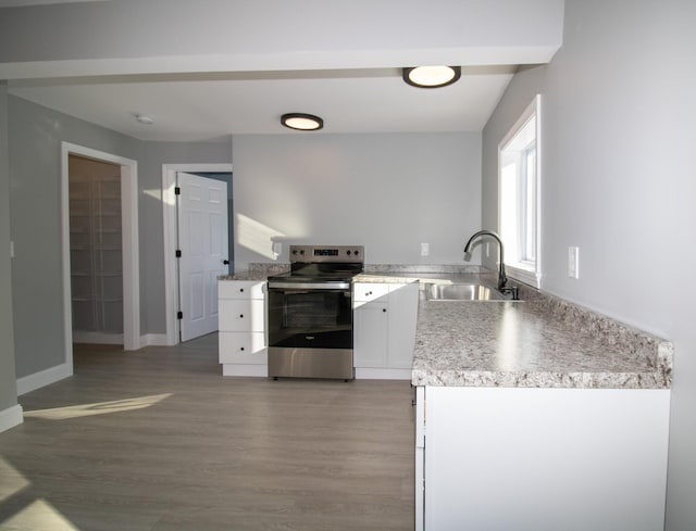 kitchen with white cabinets, electric range, sink, and hardwood / wood-style flooring