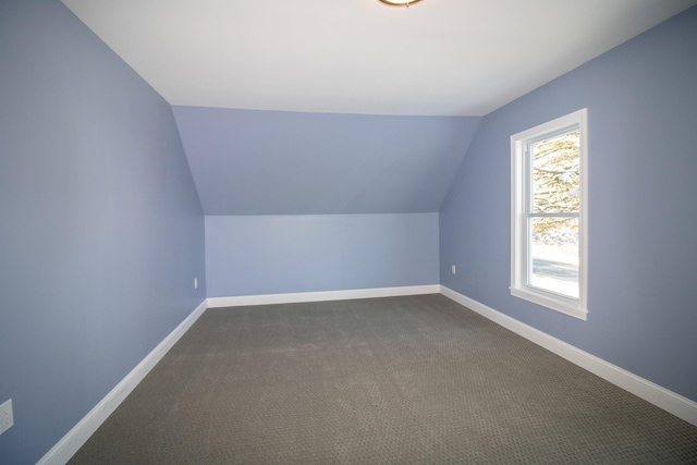 bonus room featuring vaulted ceiling and dark carpet