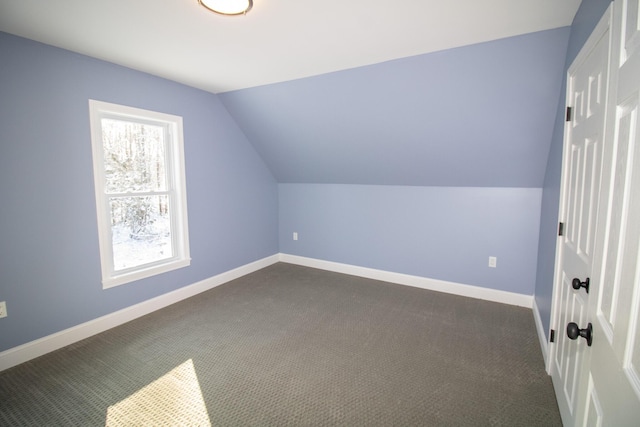 bonus room with lofted ceiling and dark carpet