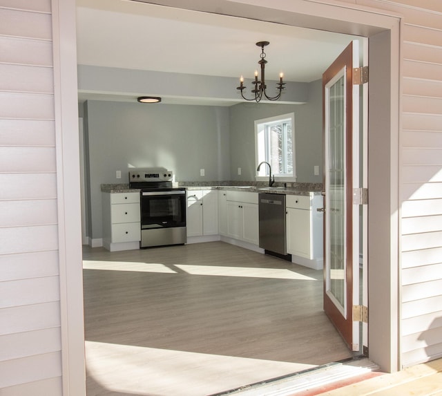 kitchen with light hardwood / wood-style floors, pendant lighting, stainless steel appliances, white cabinets, and a chandelier