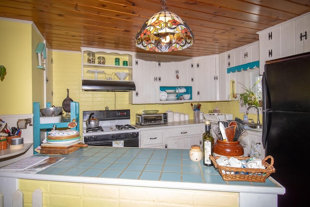 kitchen featuring black refrigerator, white cabinetry, pendant lighting, and gas range oven