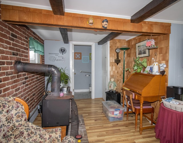 interior space featuring brick wall, light hardwood / wood-style floors, a wood stove, and beam ceiling