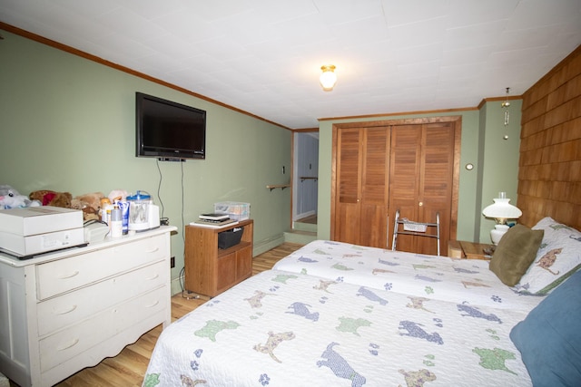 bedroom featuring ornamental molding, light hardwood / wood-style flooring, and a closet