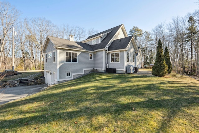 exterior space with a garage, cooling unit, and a yard