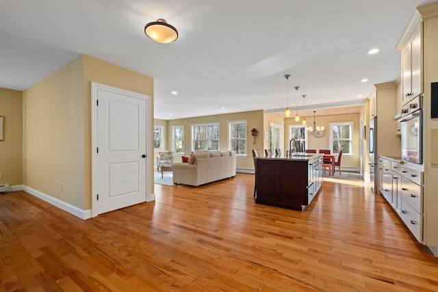 kitchen featuring decorative light fixtures, plenty of natural light, a kitchen island with sink, and stainless steel appliances