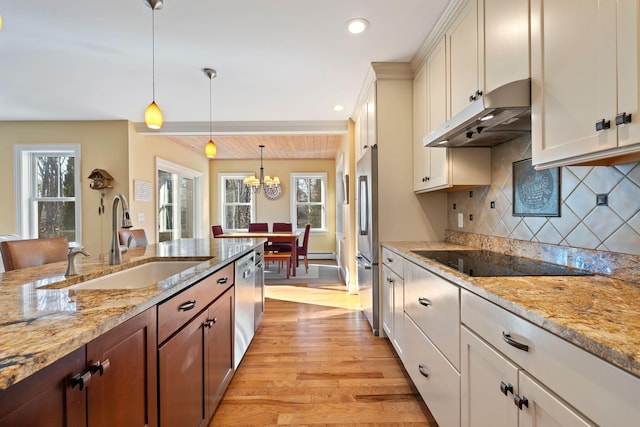 kitchen featuring stainless steel appliances, decorative backsplash, hanging light fixtures, and sink