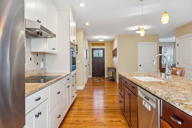 kitchen with white cabinetry, appliances with stainless steel finishes, backsplash, decorative light fixtures, and sink