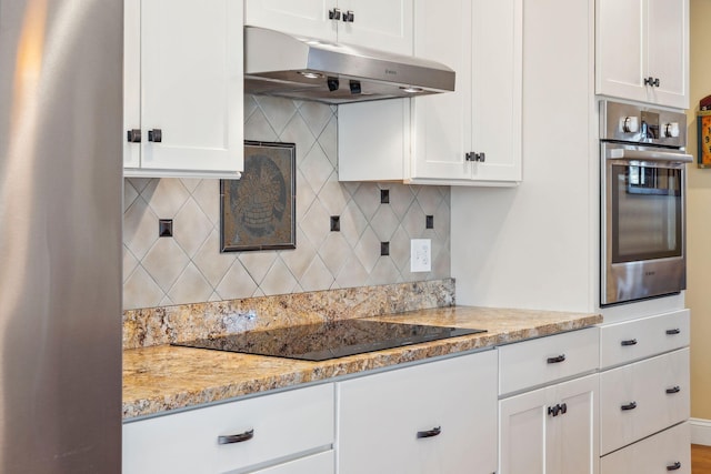 kitchen with light stone countertops, black electric stovetop, white cabinetry, and oven