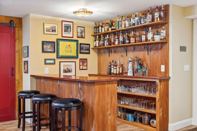 bar with a barn door and light wood-type flooring