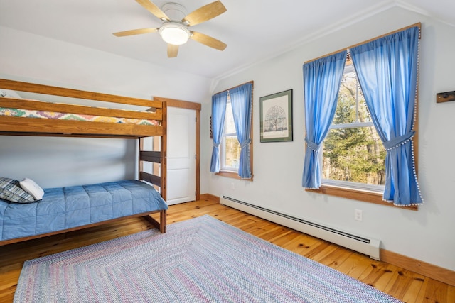 unfurnished bedroom with baseboard heating, lofted ceiling, hardwood / wood-style floors, and ceiling fan