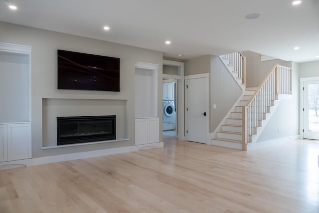 unfurnished living room with washer / dryer and light hardwood / wood-style flooring