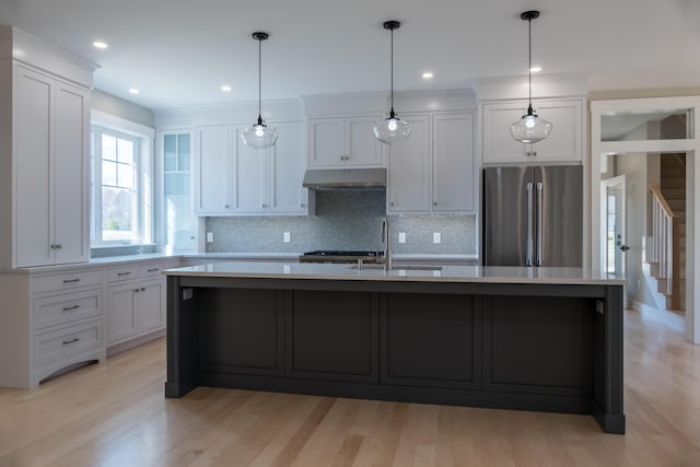 kitchen featuring stainless steel refrigerator, an island with sink, light hardwood / wood-style flooring, and white cabinets