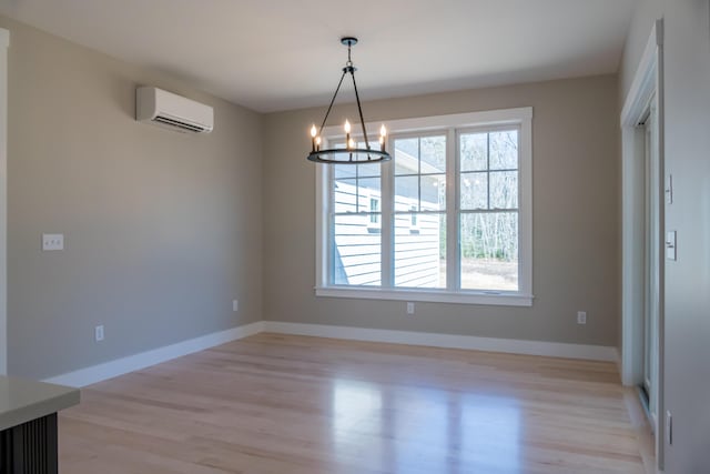 unfurnished dining area with light hardwood / wood-style floors, a chandelier, and a wall unit AC