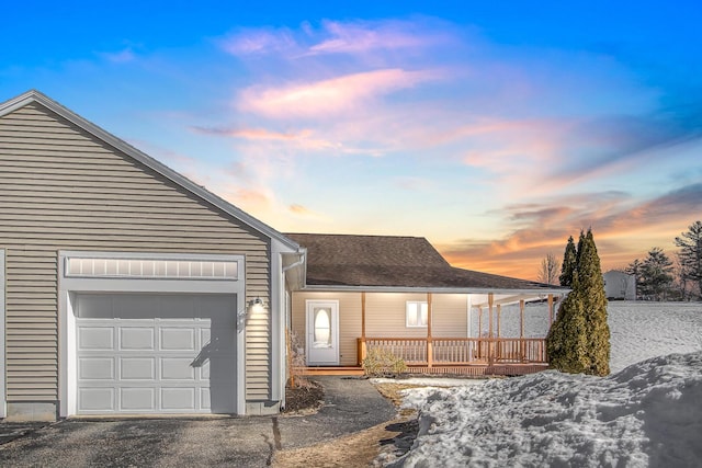 ranch-style house with a porch, a garage, roof with shingles, and aphalt driveway