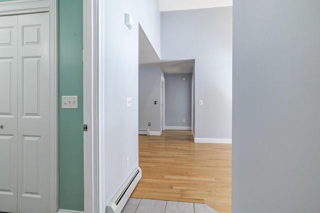 hallway featuring light wood finished floors, baseboards, and a baseboard radiator