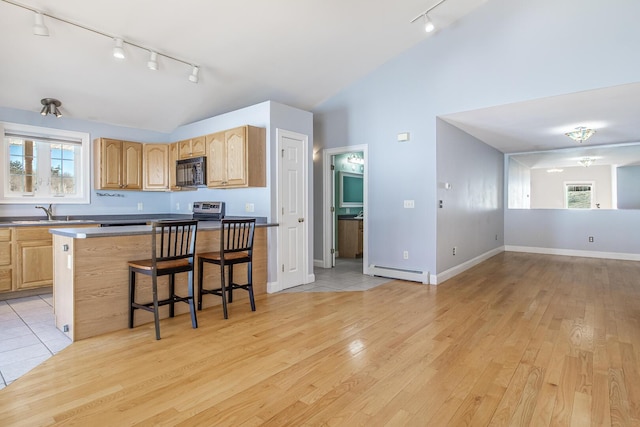 kitchen featuring light brown cabinets, a baseboard heating unit, black microwave, and vaulted ceiling