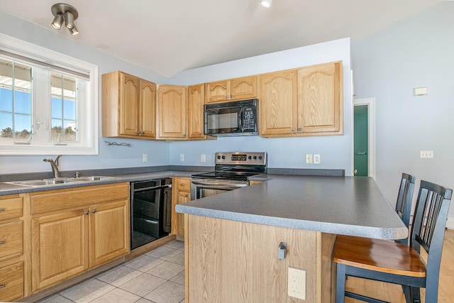 kitchen featuring a breakfast bar, a sink, stainless steel range with electric stovetop, black microwave, and dark countertops