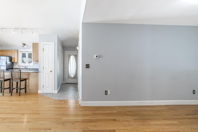 foyer entrance with track lighting, light wood-style flooring, and baseboards