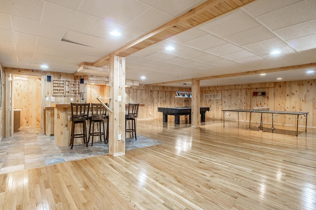 interior space with wood finished floors, wooden walls, and a dry bar