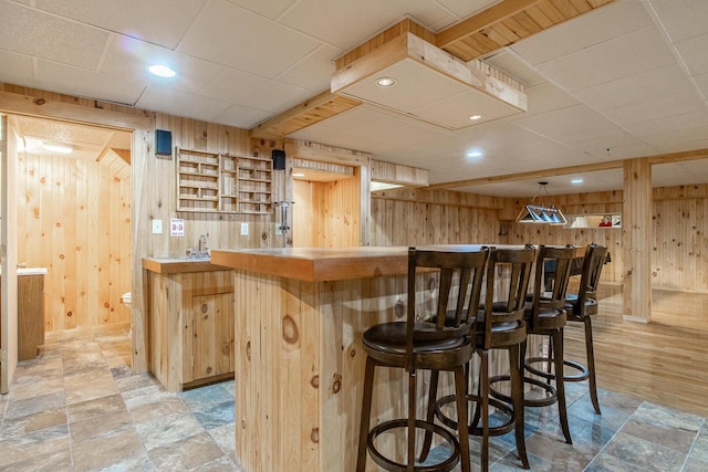 bar featuring stone finish flooring, recessed lighting, wood walls, and indoor bar