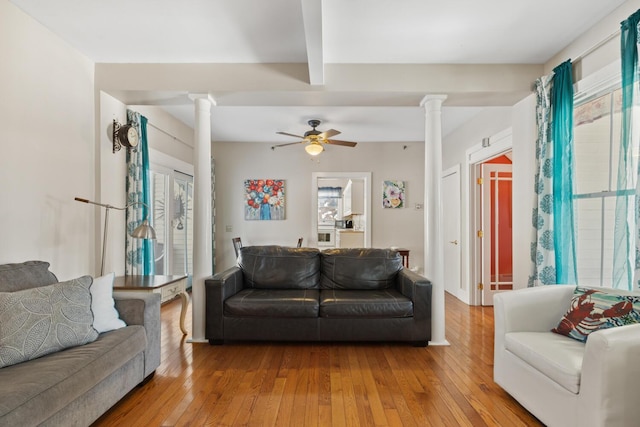 living room with a healthy amount of sunlight, beam ceiling, light hardwood / wood-style floors, and decorative columns