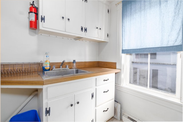 kitchen featuring sink, a baseboard radiator, and white cabinetry