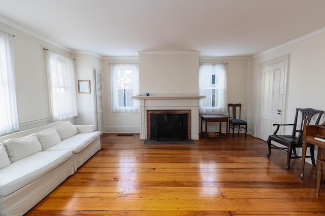 living room with a brick fireplace, ornamental molding, and hardwood / wood-style flooring