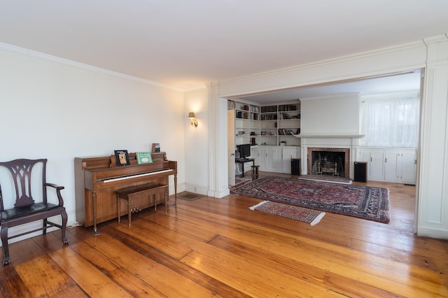 living room featuring a brick fireplace, hardwood / wood-style floors, and ornamental molding