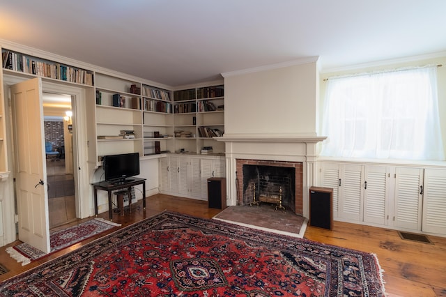 living room with a brick fireplace, hardwood / wood-style floors, and crown molding