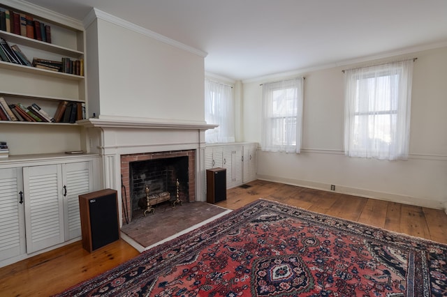 living room with light hardwood / wood-style floors, a brick fireplace, and ornamental molding