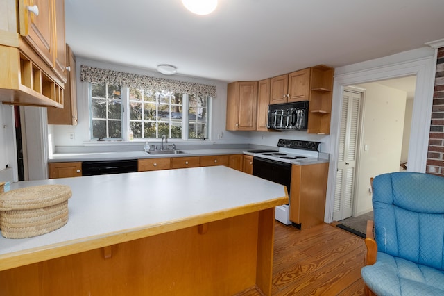 kitchen with black appliances, kitchen peninsula, a breakfast bar, sink, and light hardwood / wood-style flooring