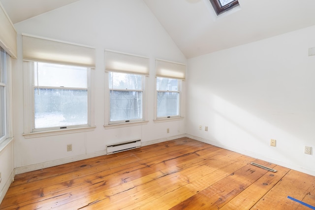 unfurnished room featuring baseboard heating, light wood-type flooring, and lofted ceiling with skylight