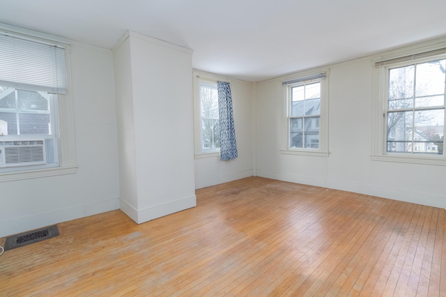 unfurnished room with light hardwood / wood-style floors, cooling unit, and plenty of natural light