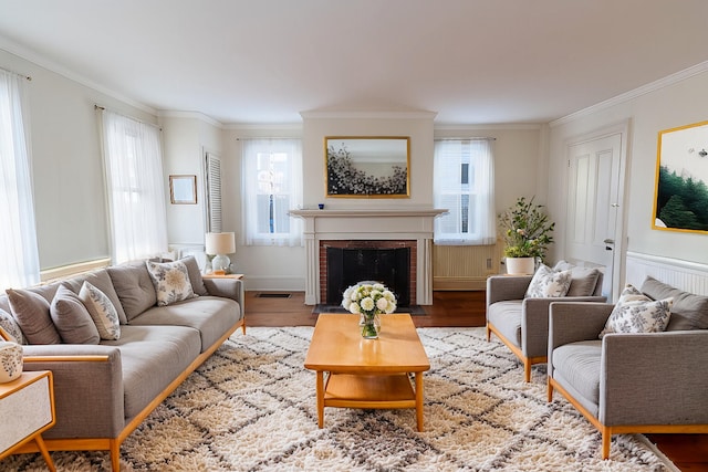 living room with hardwood / wood-style flooring, a fireplace, a wealth of natural light, and crown molding