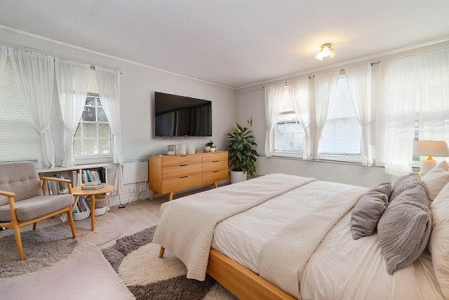 bedroom featuring ornamental molding and light hardwood / wood-style flooring