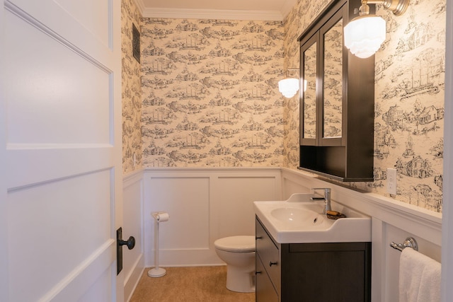 bathroom featuring wallpapered walls, a decorative wall, a wainscoted wall, toilet, and vanity
