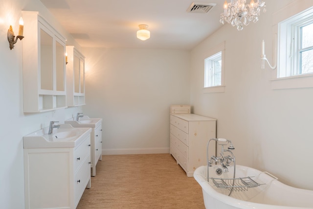 bathroom with vanity, a freestanding bath, a chandelier, and baseboards