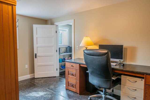 office area featuring concrete floors and baseboards