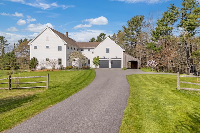 view of front of home with asphalt driveway, a garage, and a chimney